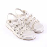 White women's sandals with scalloped cutouts and crystal accents, open toes and ankle buckles.