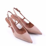 Nude pink pointed-toe slingback pumps with thin ankle straps and kitten heels on a white background.