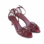 Burgundy strappy high-heeled sandals with knotted front and ankle strap on a white background