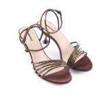 Brown suede strappy heeled sandals with gold-toned studs and an ankle buckle, open-toe design on white background