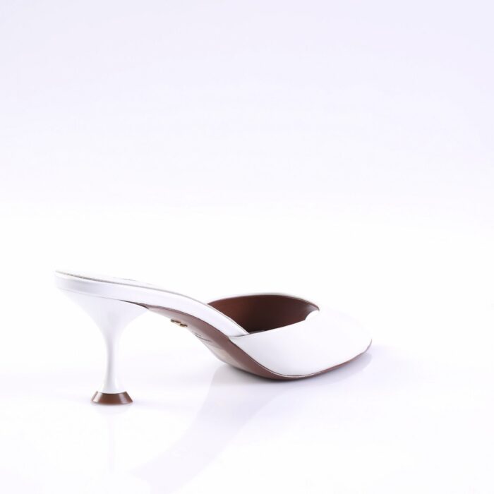White women's mule with a curved stiletto heel on a glossy white surface.