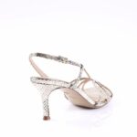 Gold snakeskin-printed strappy high-heeled sandal with an ankle strap on a white background.