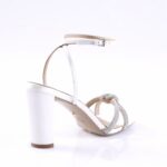 White high-heeled ankle-strap sandal with rhinestone-adorned front straps on a white background