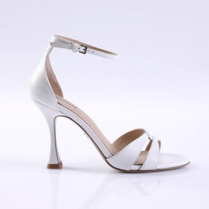 White women's high-heeled sandal with an ankle strap and open toe on a reflective surface, profile view.