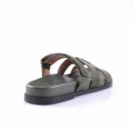 Olive green suede sandal with multiple straps and a flat black sole, shown from a rear-side angle.
