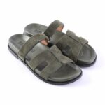 Olive green suede slide sandals with two wide straps across the foot and a black sole on a white background