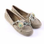 Beige suede loafers with braided laces and pastel flower embellishments on the toe