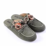Green suede slip-on loafers (mules) with braided laces and orange-brown floral embellishment on the vamp, viewed from side angle.