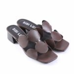 Brown leather heeled slide sandals with large circular cutout straps and a chunky block heel.”] ,