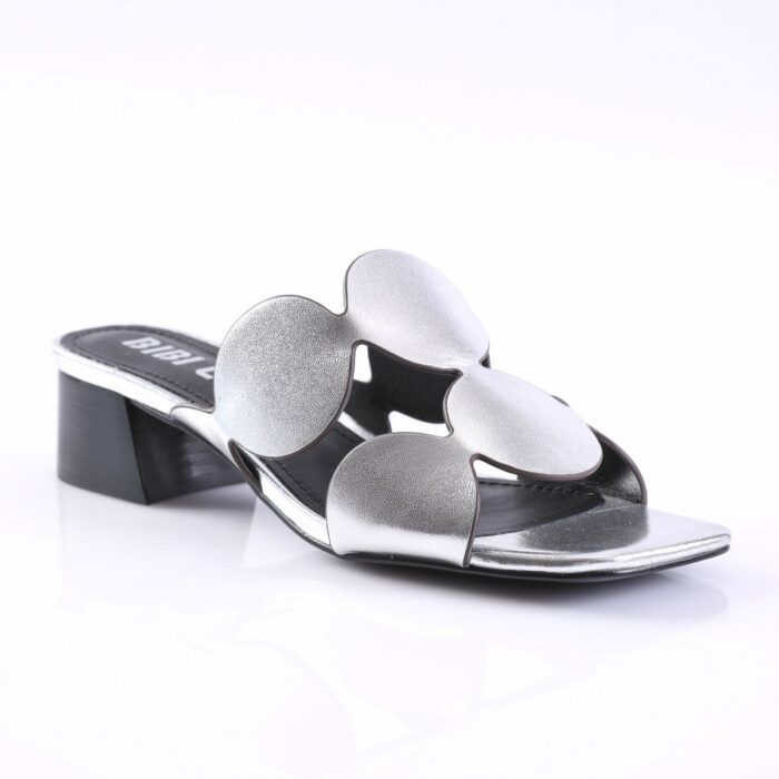 Open-toe silver metallic slide sandal with a large flower-shaped strap and a short block heel.