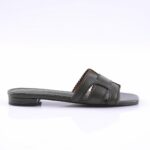 Dark green slide sandal with two wide straps featuring scalloped edges and small cutouts, flat sole.