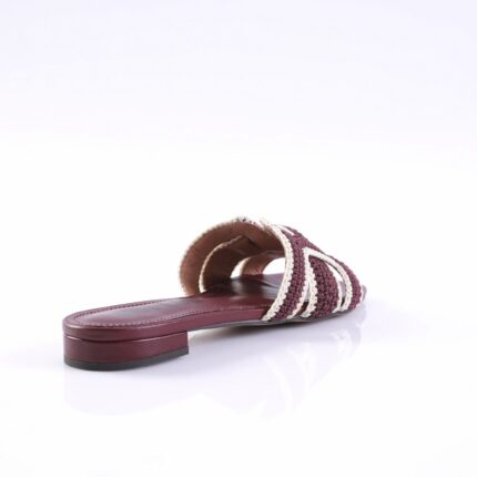 Maroon braided slide sandal with cream straps and a low heel on a white background, viewed from the side.