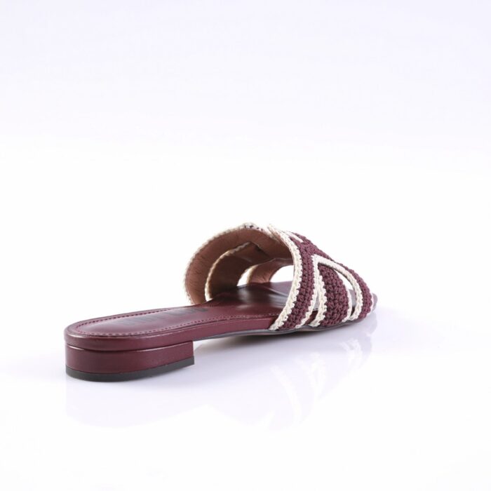 Maroon braided slide sandal with cream straps and a low heel on a white background, viewed from the side.