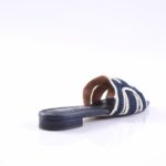 Navy blue crocheted slide sandal with white striped straps on a flat sole, shown from the side.