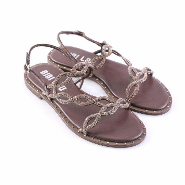 Brown flat sandals with rhinestone-encrusted, interwoven chain straps and studded edge along the sole, on white background.