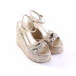 Gold metallic braided wedge sandals with ankle straps and braided front knot on a platform espadrille heel