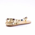 Gold strappy sandal with multiple ankle straps and colorful round studs on a tan sole, photographed sideways on white background