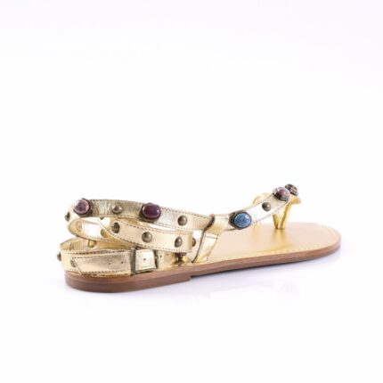 Gold strappy sandal with multiple ankle straps and colorful round studs on a tan sole, photographed sideways on white background