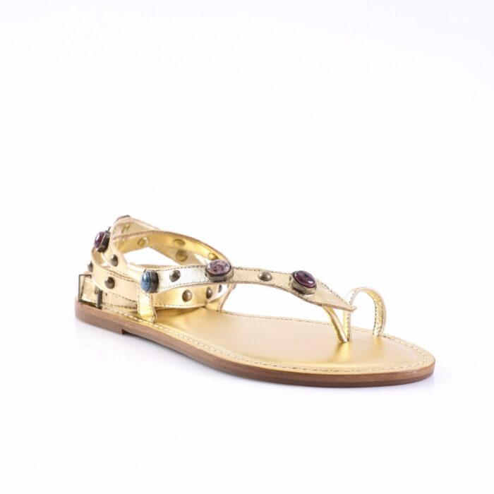 Gold-toned flat sandal with studded strap and colored gem accents, thong-style toe loop, low-profile heel.