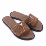 Brown slide sandals with a wide studded strap featuring multicolored rhinestones and a small gold triangle logo on each strap.