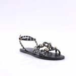 Black flat sandal with studded straps and gold-tone studs, open toe.