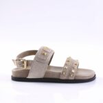 Beige suede sandal with two embellished straps and gold stud hardware, low black sole.