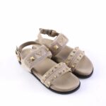 Beige strappy sandals with gold pyramid studs and buckles on a white background, casual fashion footwear for adults.