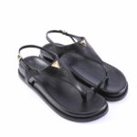 Black leather thong sandals with slingback strap and gold triangle logo plaques on the sides.