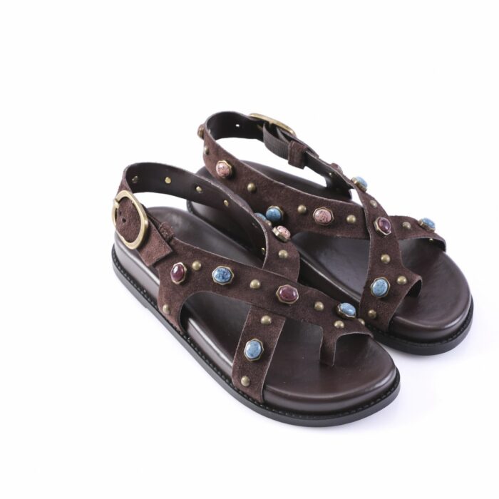 Brown suede gladiator sandals with studded straps and colorful gem accents, open-toe design on a dark sole, side buckle.