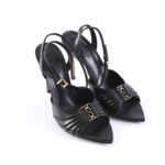 Black strappy heeled sandals with pointed toes and gold buckle detail on a white background, side view.