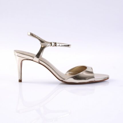Gold metallic high-heeled sandal with ankle strap on a white reflective surface, side view showing thin heel and open toe.