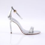 Silver snakeskin high-heeled sandal with an ankle strap and gold stud, open-toe design