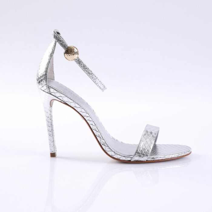 Silver snakeskin high-heeled sandal with an ankle strap and gold stud, open-toe design