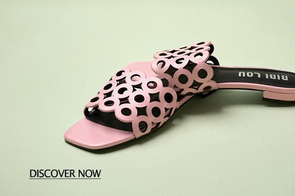 Pink slide sandal with circular cutout pattern on a pale green background; 'DISCOVER NOW' text visible in the lower-left corner of the image.