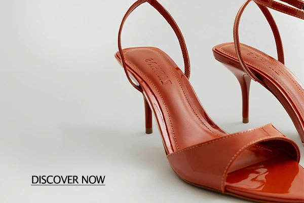 Red patent leather high-heeled sandals with slender straps on a pale background; features a 'DISCOVER NOW' call-to-action.