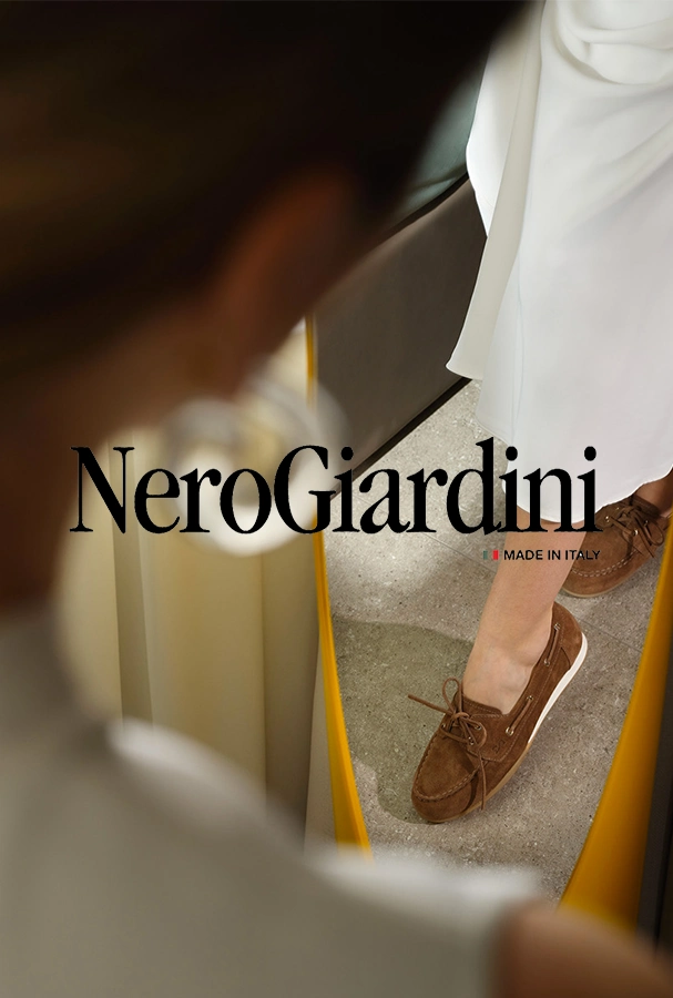 NeroGiardini fashion ad: reflection shows a person in brown suede loafers and a white dress, with 'Made in Italy' text.