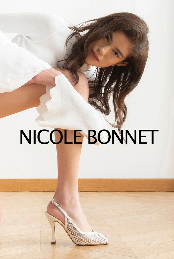 Model in a white outfit bending, wearing a white high-heeled shoe with a bold 'NICOLE BONNET' text overlay.