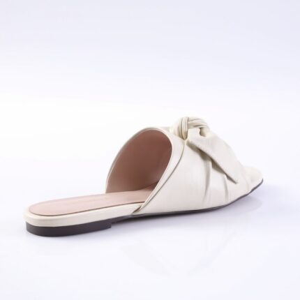 Cream-colored slide sandal with a knotted strap and open toe for women, on a flat sole.