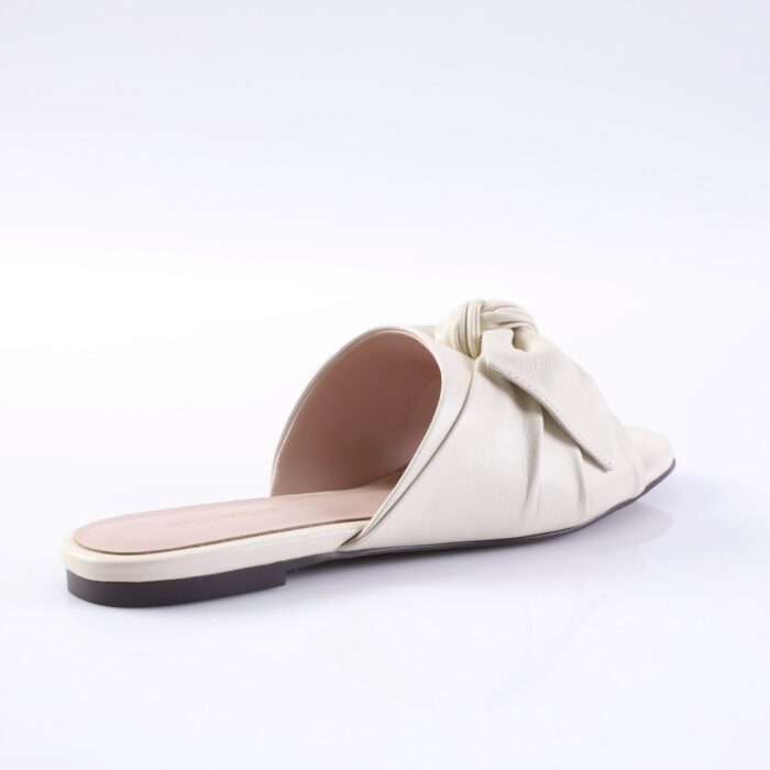 Cream-colored slide sandal with a knotted strap and open toe for women, on a flat sole.