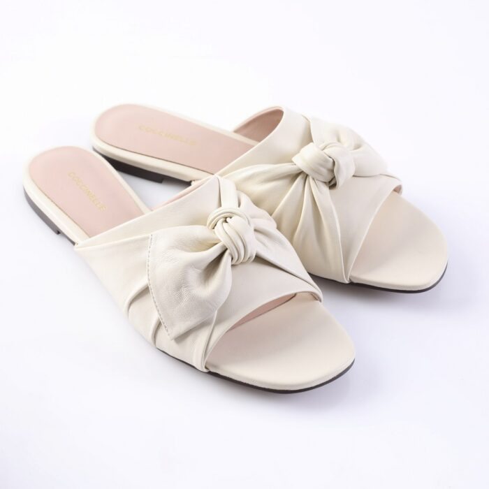 Cream leather slide sandals with large knotted front straps and open toes.