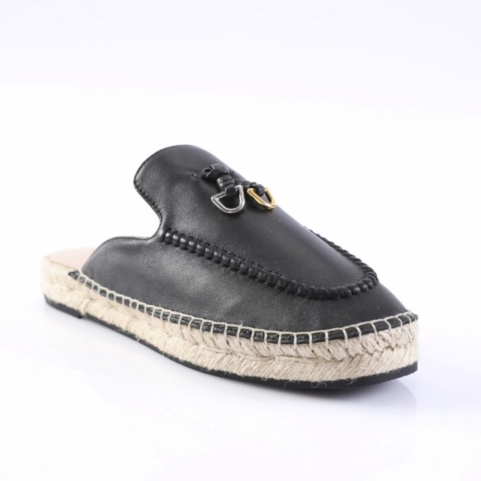 Black leather moccasin-style espadrille with a braided rope sole and metal hardware detail on the vamp, photographed from a side angle for product view