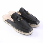 Black leather espadrille slip-ons with a braided jute sole and decorative metal hardware on the vamp.
