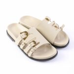Beige leather sandals with multiple gold-buckle straps and a black sole, shown as a pair.
