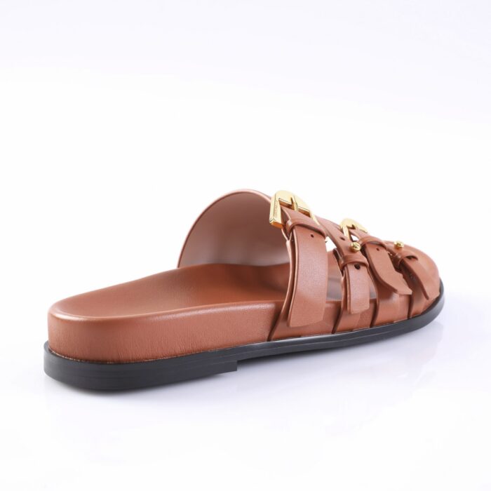 Brown leather slide sandal with two gold-buckle straps and a black sole, shown from a side angle.