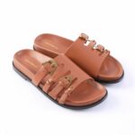 Brown leather slide sandals with three buckled straps and gold hardware