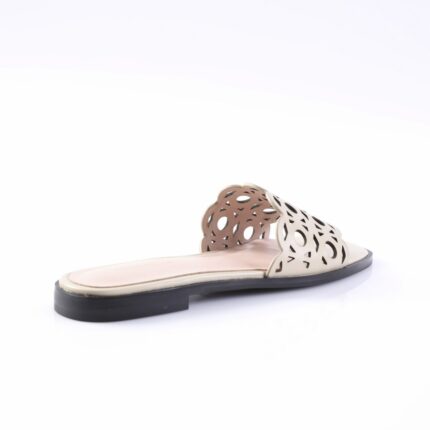 Beige women's flat sandal with a cutout floral pattern on the strap and a black sole