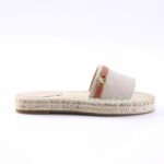 Beige espadrille slide with rope-wrapped sole and fabric strap featuring pink leather accent and gold hardware from a side view (product photo)