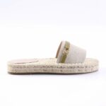 Beige espadrille slide sandal with a woven jute sole and beige fabric strap with gold hardware.