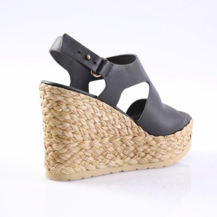 Black leather wedge sandal with braided jute platform and ankle strap, open toe on white background, side view showing heel height.
