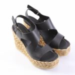 Black leather wedge sandals with braided jute sole and ankle strap closures.